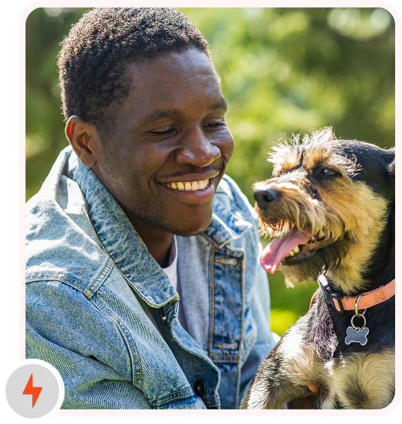 A man stroking his dog, smiling.